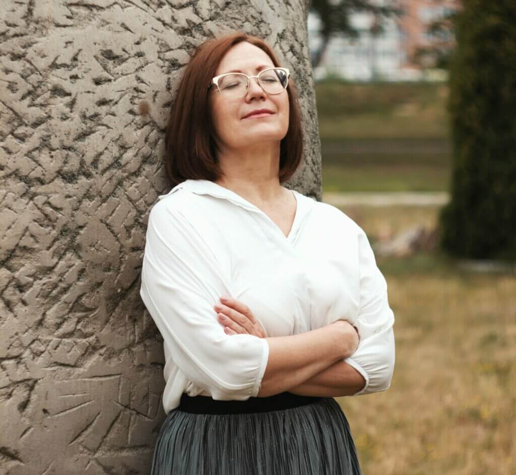 Middle aged woman relaxing against a pillar